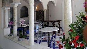 An indoor courtyard with stone columns, a tiled floor, and a round table with chairs. - Hotel Croce di Amalfi (Amalfi)