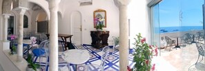 Enjoy breathtaking sea views from this room's balcony, featuring a comfortable seating area and a potted plant.