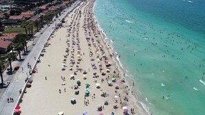 A beach with rows of umbrellas and people. - Çesme Sirin Villa Otel (Cesme)