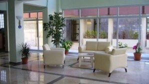 A spacious lobby with a large seating area, multiple potted plants, and large windows providing natural light. - Çesme Sirin Villa Otel (Cesme)