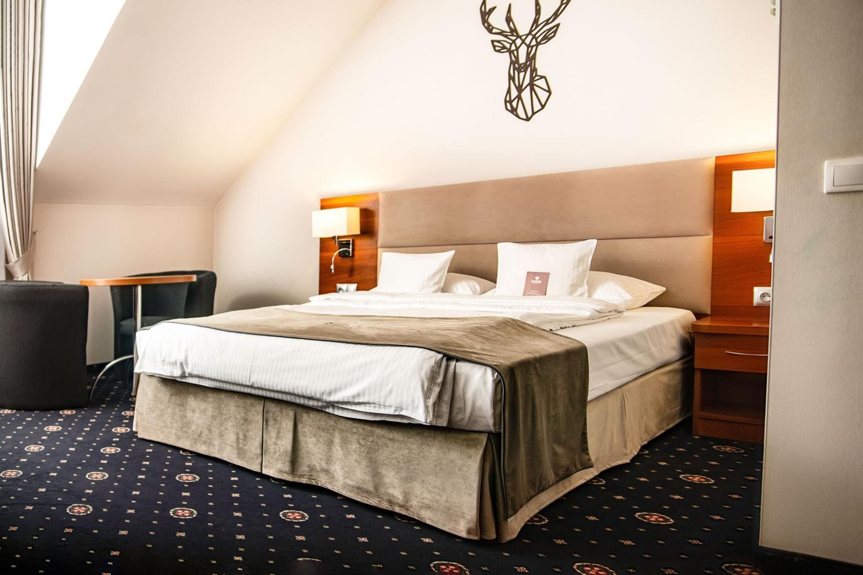 A hotel room with a bed, a nightstand, a lamp, and a wall decoration.