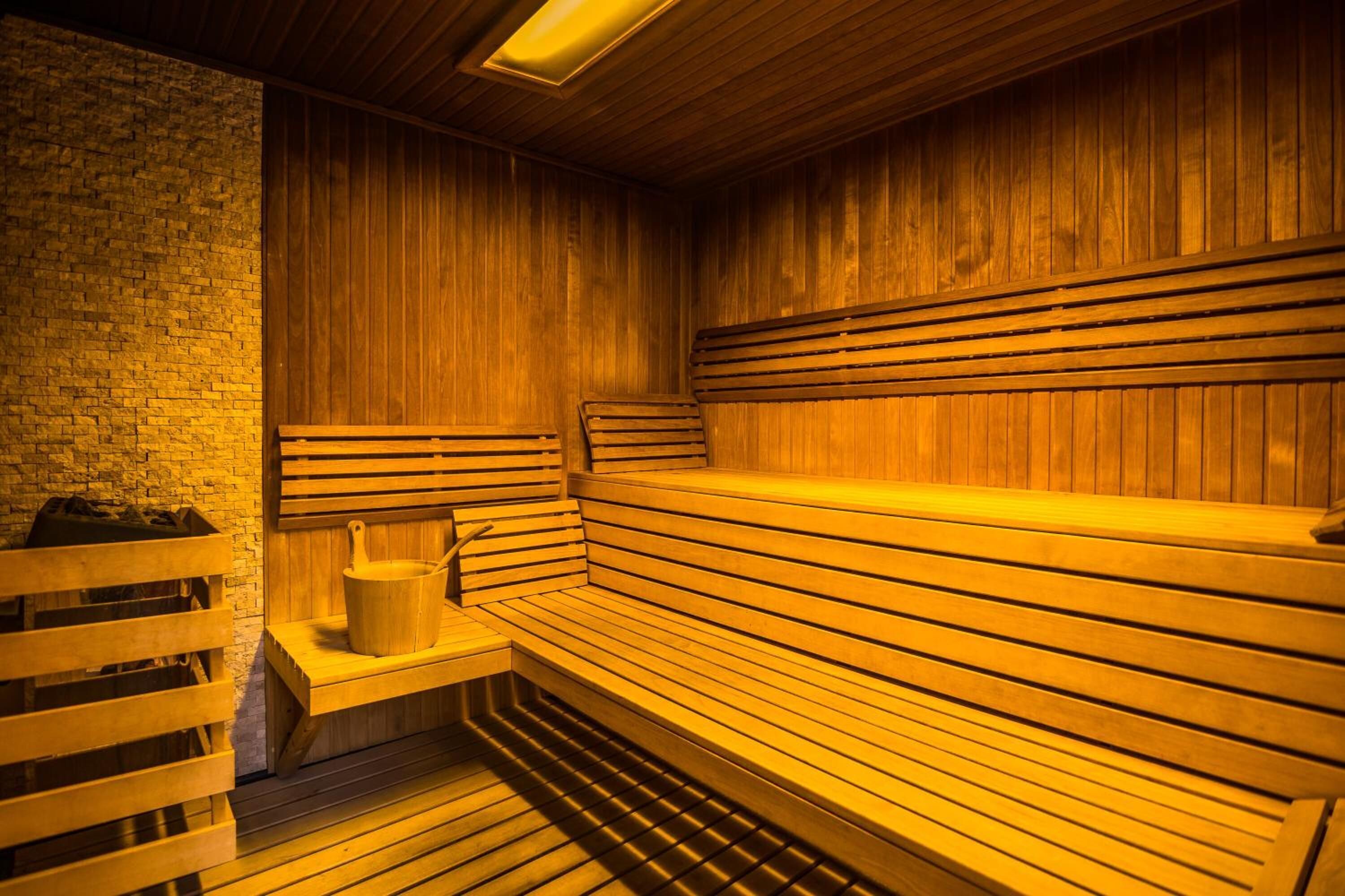 A sauna with wooden benches and a brick wall.