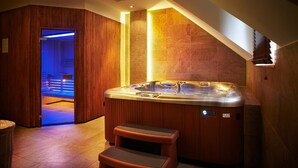 Un moderno spa con hidromasaje, paneles de madera y una sauna iluminada en azul.