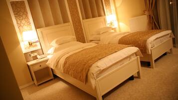 A hotel room with two beds, a nightstand with a phone, and a lamp.