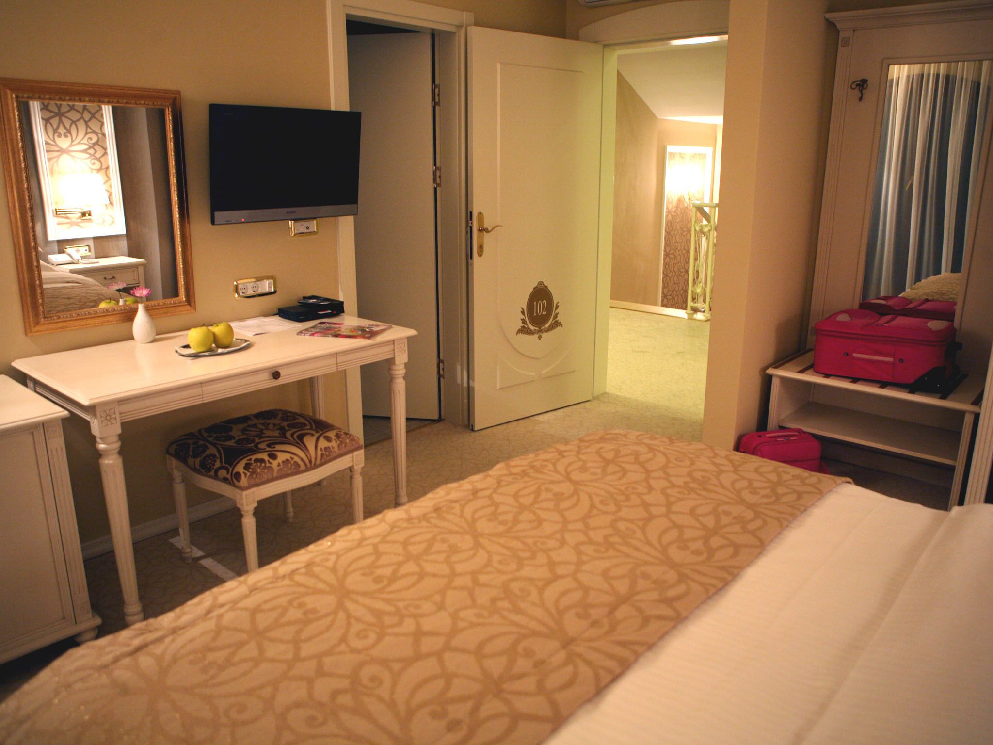A hotel room with a bed, a desk, a chair, a television, and a wardrobe.