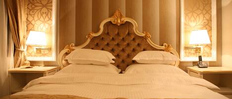 A large bed with a tufted headboard, two bedside tables with lamps, and a mirror on each side.