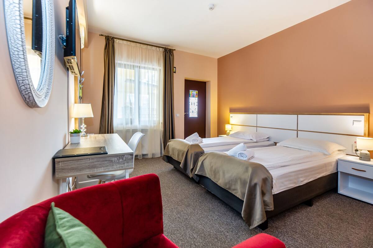 A hotel room with a bed, a desk, a chair, a TV, and a mirror.