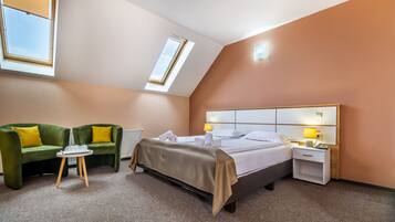A hotel room with a bed, a green sofa, a small table, a nightstand, and a skylight.