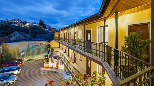 A hotel with a covered outdoor area, multiple balconies, and a view of the surrounding landscape. - Long Street Hotel (Brasov)