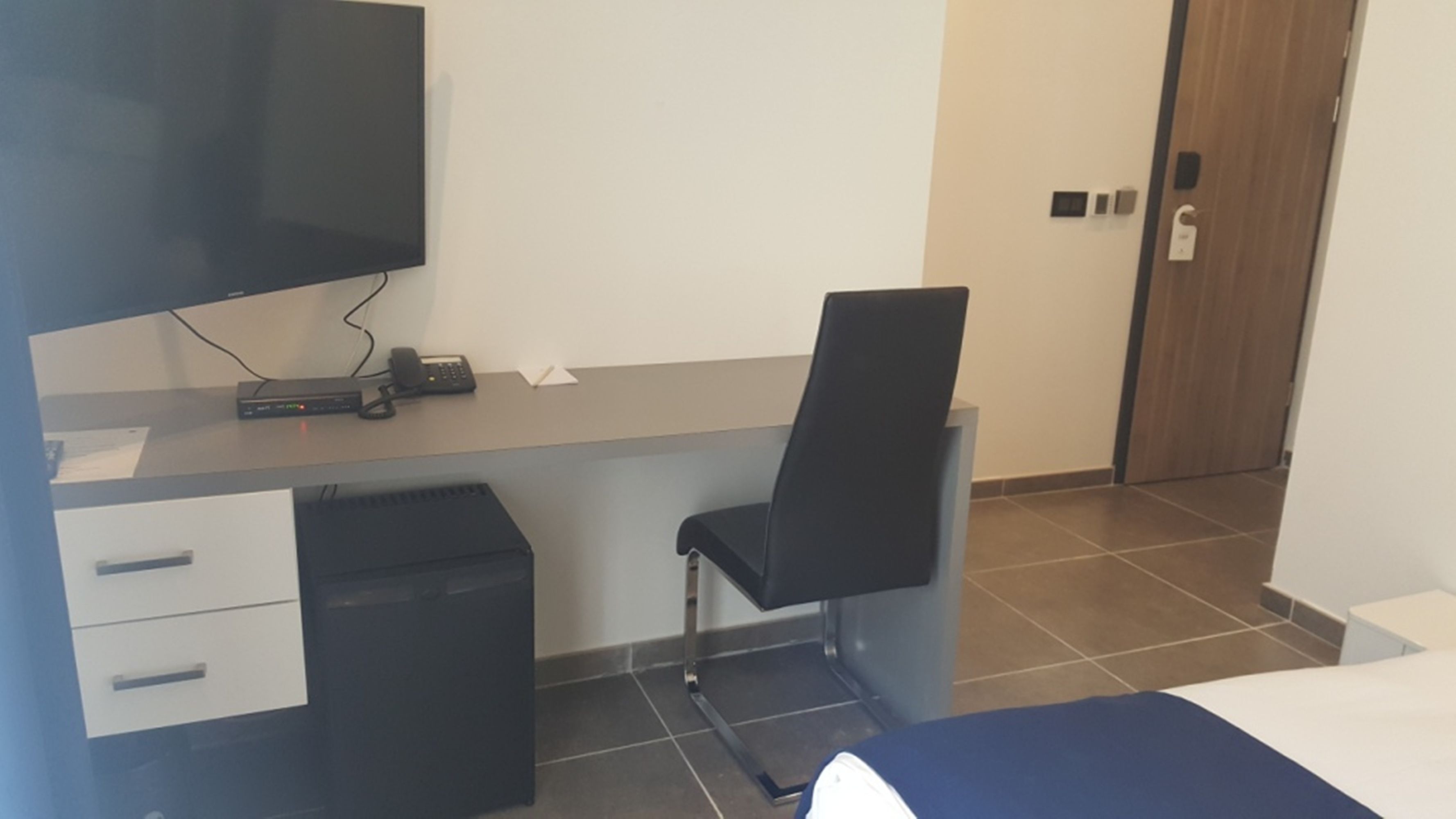 Une petite pièce moderne, équipée d’un bureau, d’une chaise et d’un lit.
