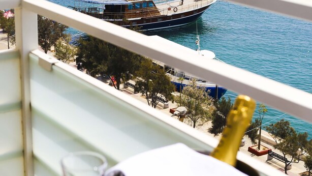A balcony with a view of the sea, a bottle of champagne, and a glass. - Pebbles Boutique Aparthotel (Sliema)