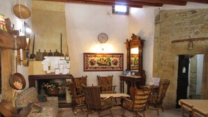 A cozy living room with a fireplace, wooden furniture, and a clock on the wall. - Sa Dom'e Forru (Collinas)