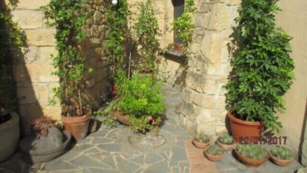 An outdoor stone pathway with potted plants and a stone wall. - Sa Dom'e Forru (Collinas)