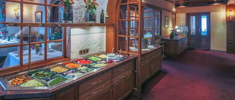 A buffet area with various food stations, wooden cabinets, and a red carpeted floor.