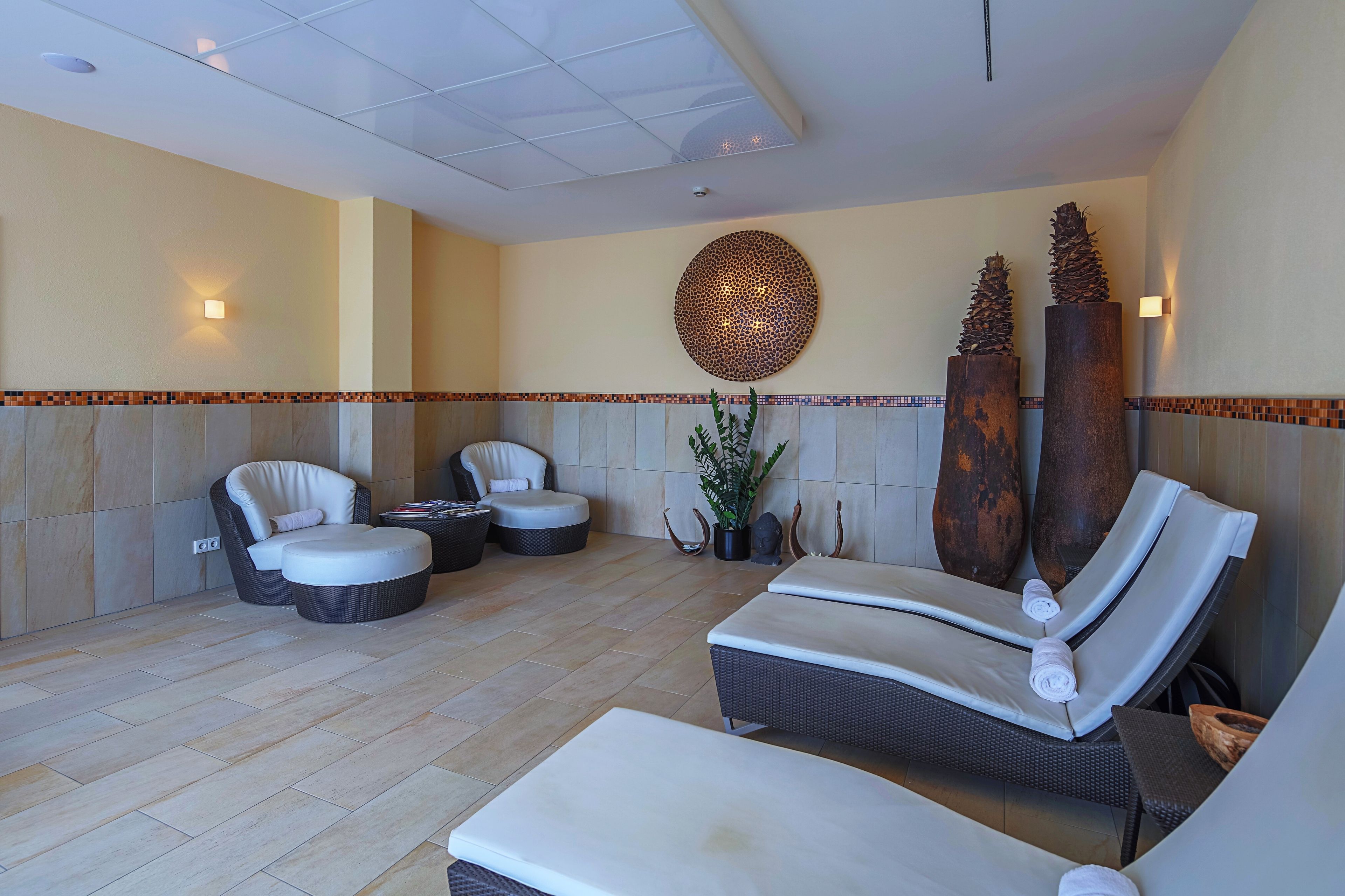 Ein Wellnessbereich mit Liegestühlen, einer Massageliege und Dekorationselementen.