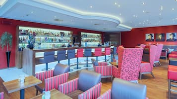 Eine moderne Bar mit verschiedenen Sitzmöglichkeiten, darunter Boxsitzgelegenheiten und Barhocker, sowie einer gut sortierten Bar.