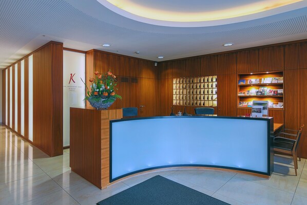 A reception desk with a curved design, wooden paneling, and a glass display case. - Hotel-Restaurant Kunz (Pirmasens)