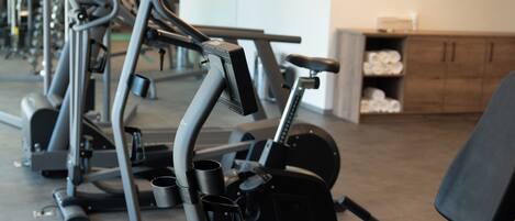 A gym with various exercise machines, including treadmills and elliptical trainers, arranged in rows.