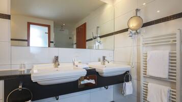 Un baño moderno con dos lavamanos, un espejo, un perchero y un toallero calefactado.