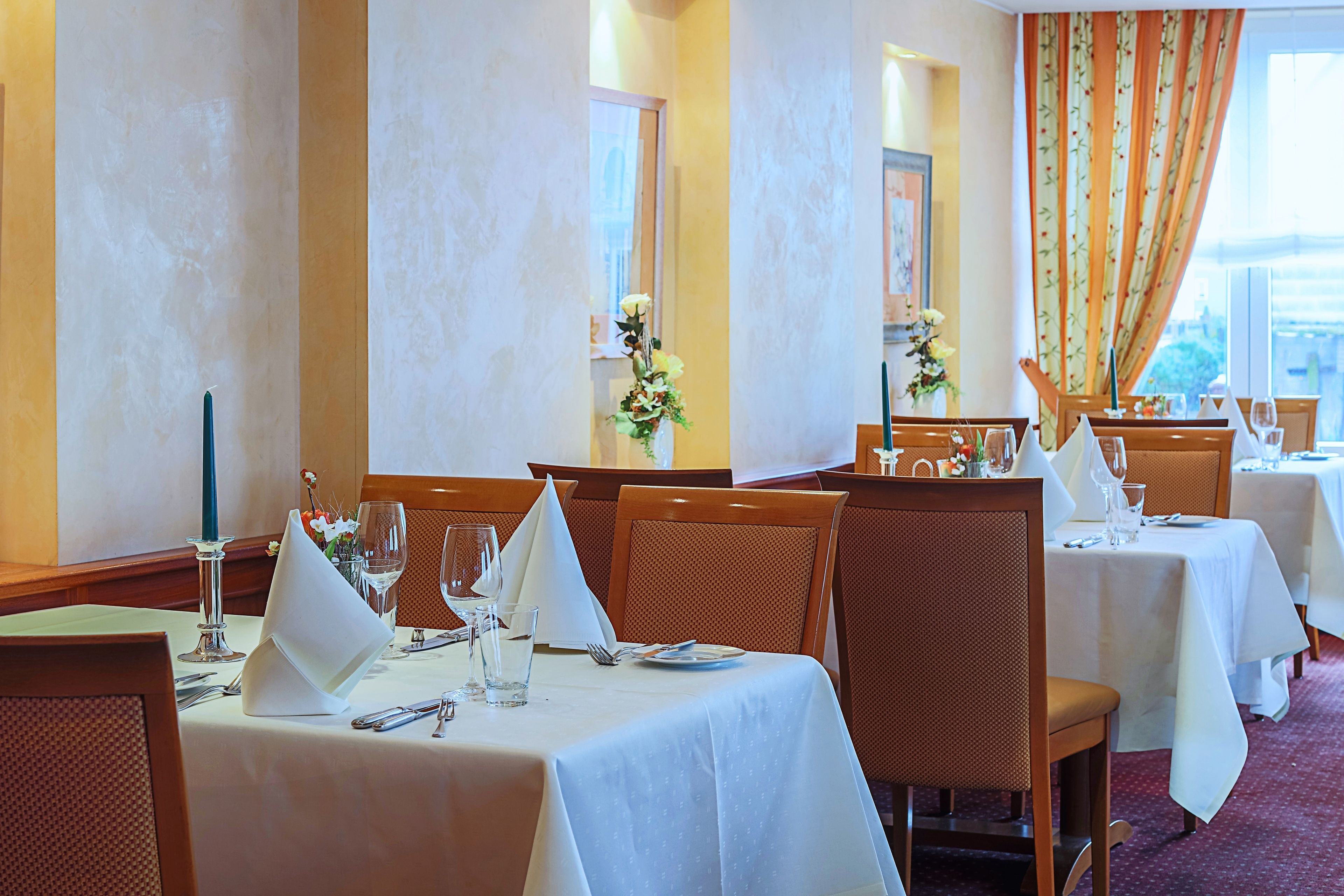 Un restaurante con mesas dispuestas para comer, con manteles blancos y sillas de madera.