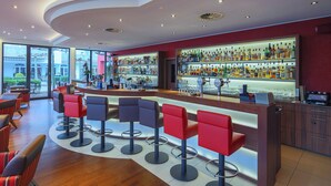 Een moderne bar met een gebogen toonbank, meerdere barkrukken, en een uitgebreide keuze aan flessen en glazen op planken.