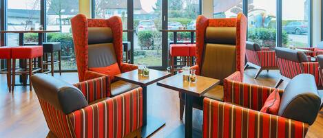 A modern restaurant with striped red and brown chairs, large windows, and a view of the parking lot.