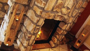 Una chimenea de piedra con fuego, una puerta de madera y un suelo de baldosas.