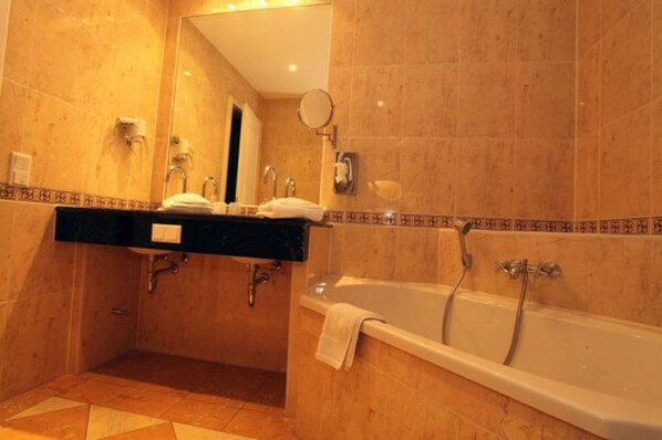 A bathroom with a bathtub, a sink with a mirror, and a towel rack.