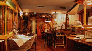 Un acogedor interior de restaurante con mobiliario de madera, una gran rueda de madera y decoración de estilo antiguo.