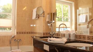 A bathroom with a bathtub, a sink with a mirror, and a towel rack.