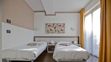 Habitación de hotel con dos camas, techo con diseño geométrico, una obra de arte en la pared y una ventana con cortinas.