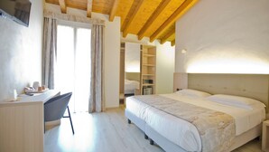 Un dormitorio con cama, escritorio y silla. Hay un armario y un televisor montado en la pared.