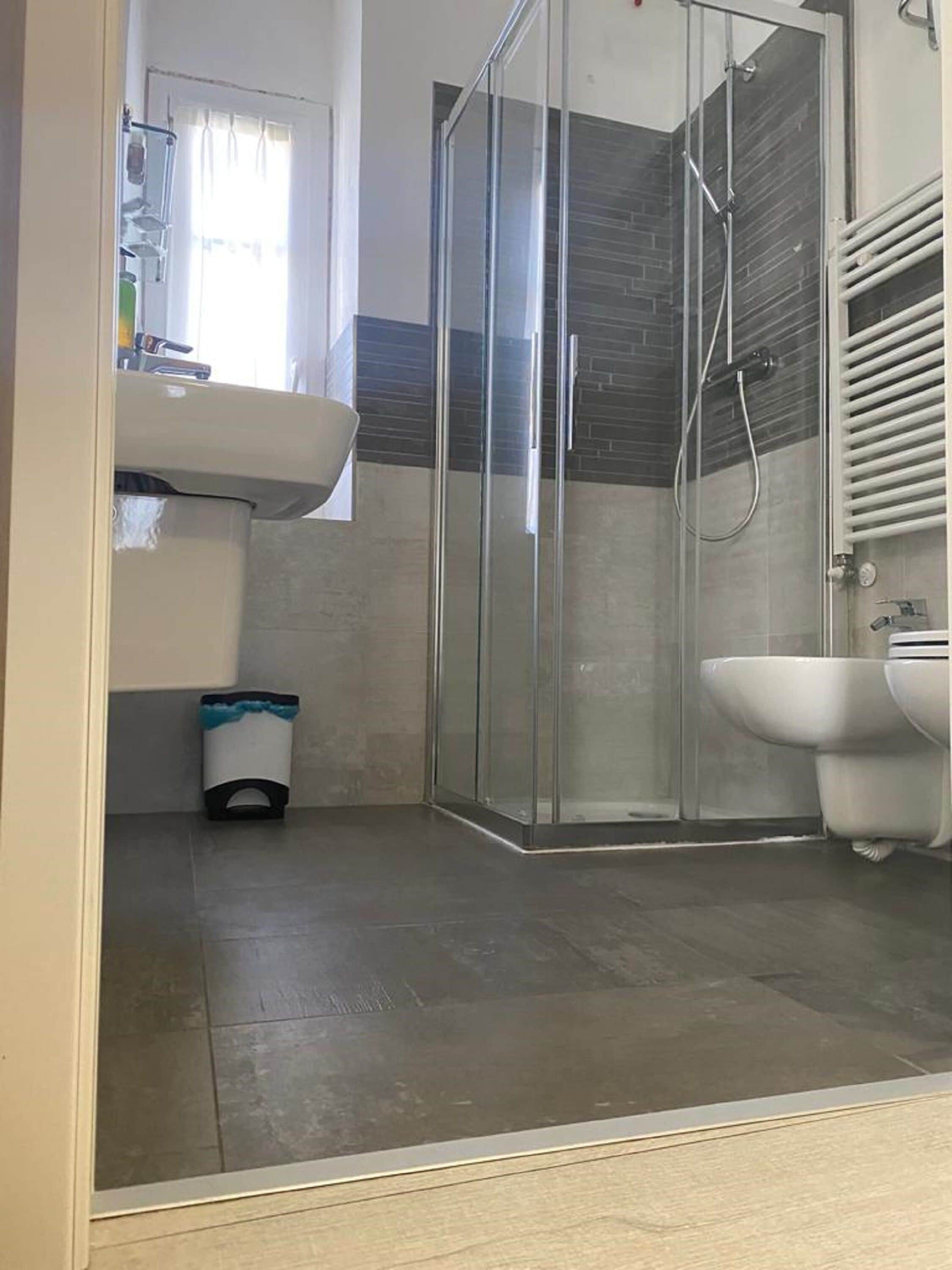Un baño moderno con cabina de ducha de vidrio, lavamanos pedestal y bidé.