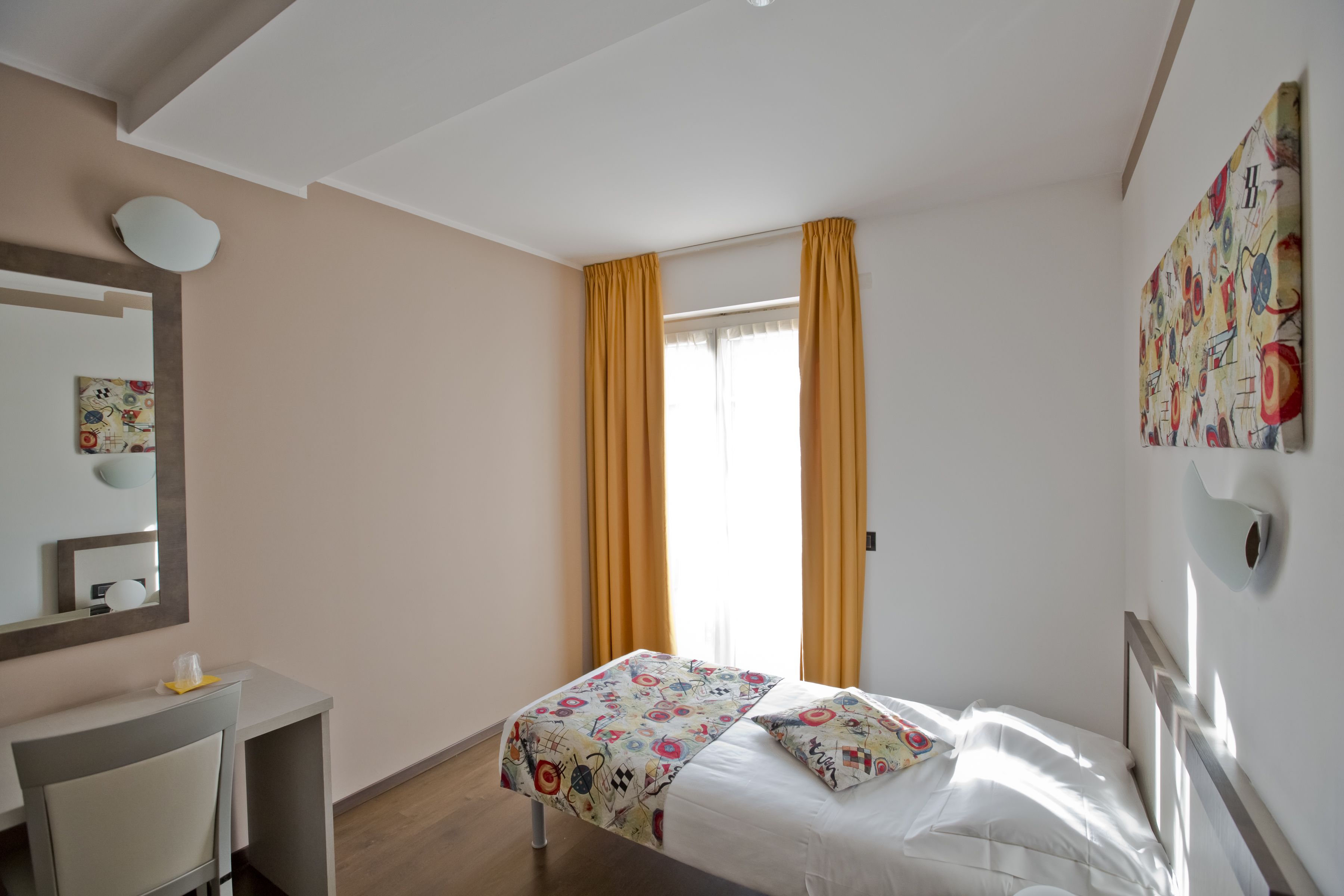 Habitación de hotel con cama, escritorio y ventana con cortinas.