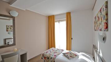 Habitación de hotel con cama, escritorio y ventana con cortinas.