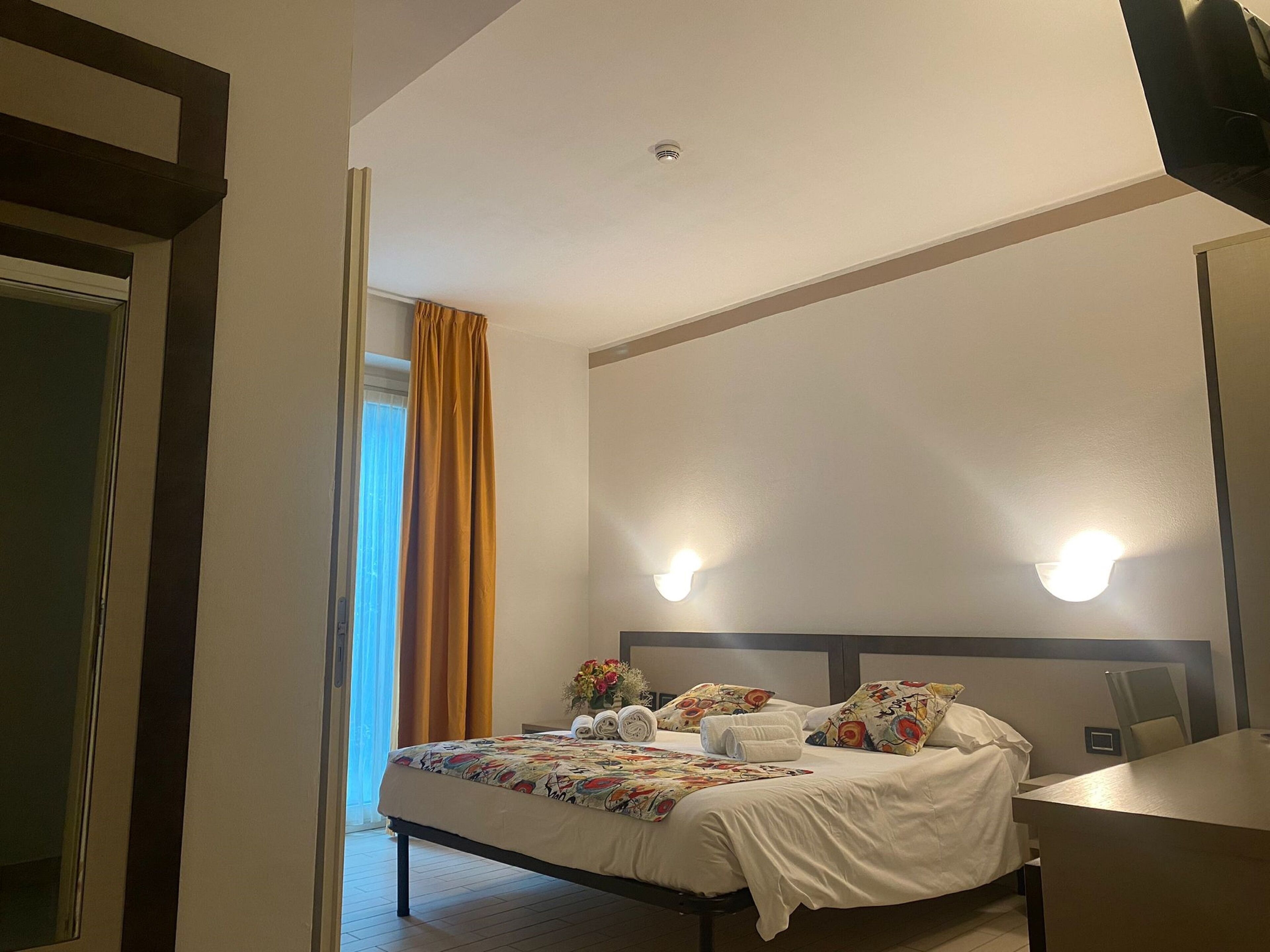 Una camera d'albergo con un letto, una scrivania e uno specchio.