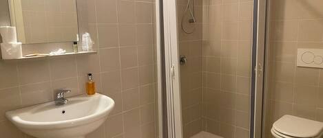 A bathroom with a shower, sink, and toilet.