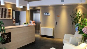 Zona de recepción de un hotel con mostrador, asientos e indicación del nombre del hotel.