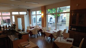 Un restaurante con varias mesas, una zona de bar y amplios ventanales que dan a la calle.