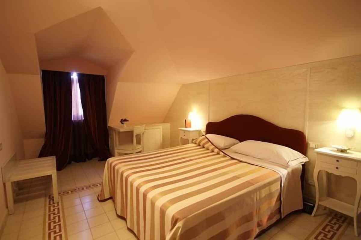 A hotel room with two beds, a desk, a chair, and a window with curtains.