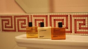 Three toiletry bottles on a white sink with a patterned tile backsplash. - Palace Hotel Una Nuova Strada (Nocera Terinese)