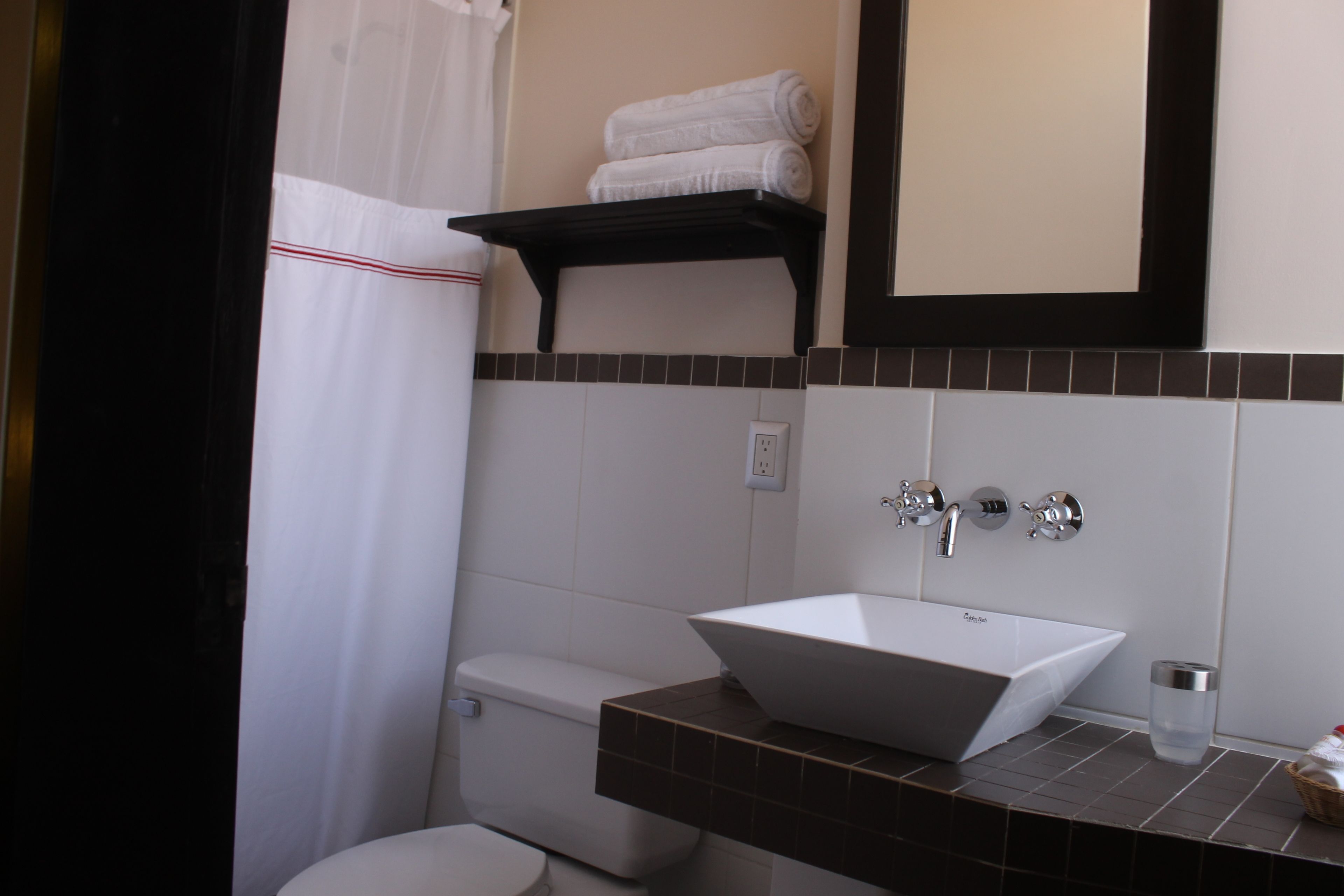 Un baño con lavamanos blanco, inodoro, toallero y espejo.