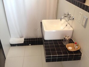 A bathroom with a white sink, black tiled floor, a towel, and a basket with toiletries.