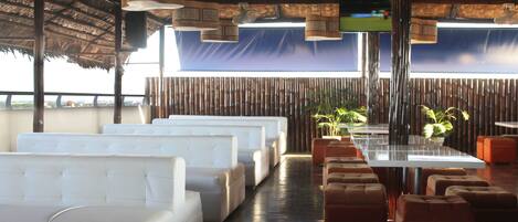 Un restaurante con asientos blancos y marrones, paredes de bambú y luces colgantes.
