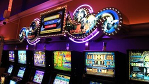 Uma fileira de máquinas de jogo com telas iluminadas e um letreiro de neon acima.