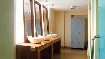 Une salle de bain avec trois lavabos, un meuble-lavabo en bois, des miroirs et un meuble bleu.