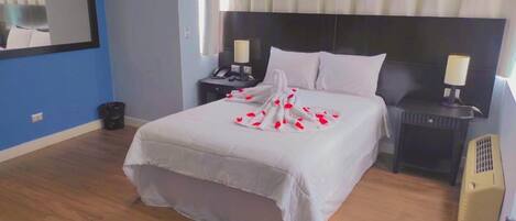 Un dormitorio ordenado con una cama grande, dos mesitas de noche, un espejo y un calentador.