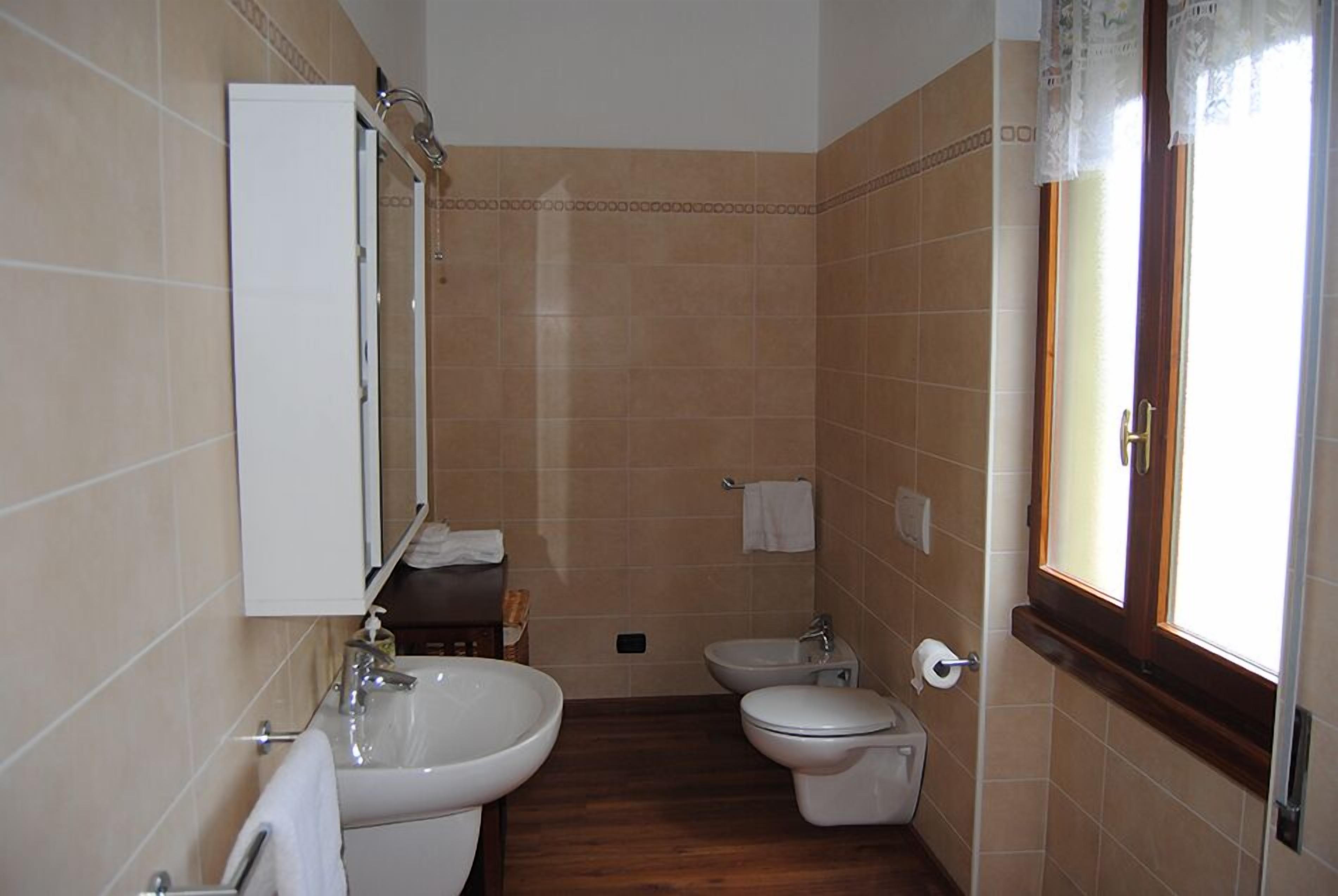 Un baño con lavamanos, bidé, inodoro y espejo.
