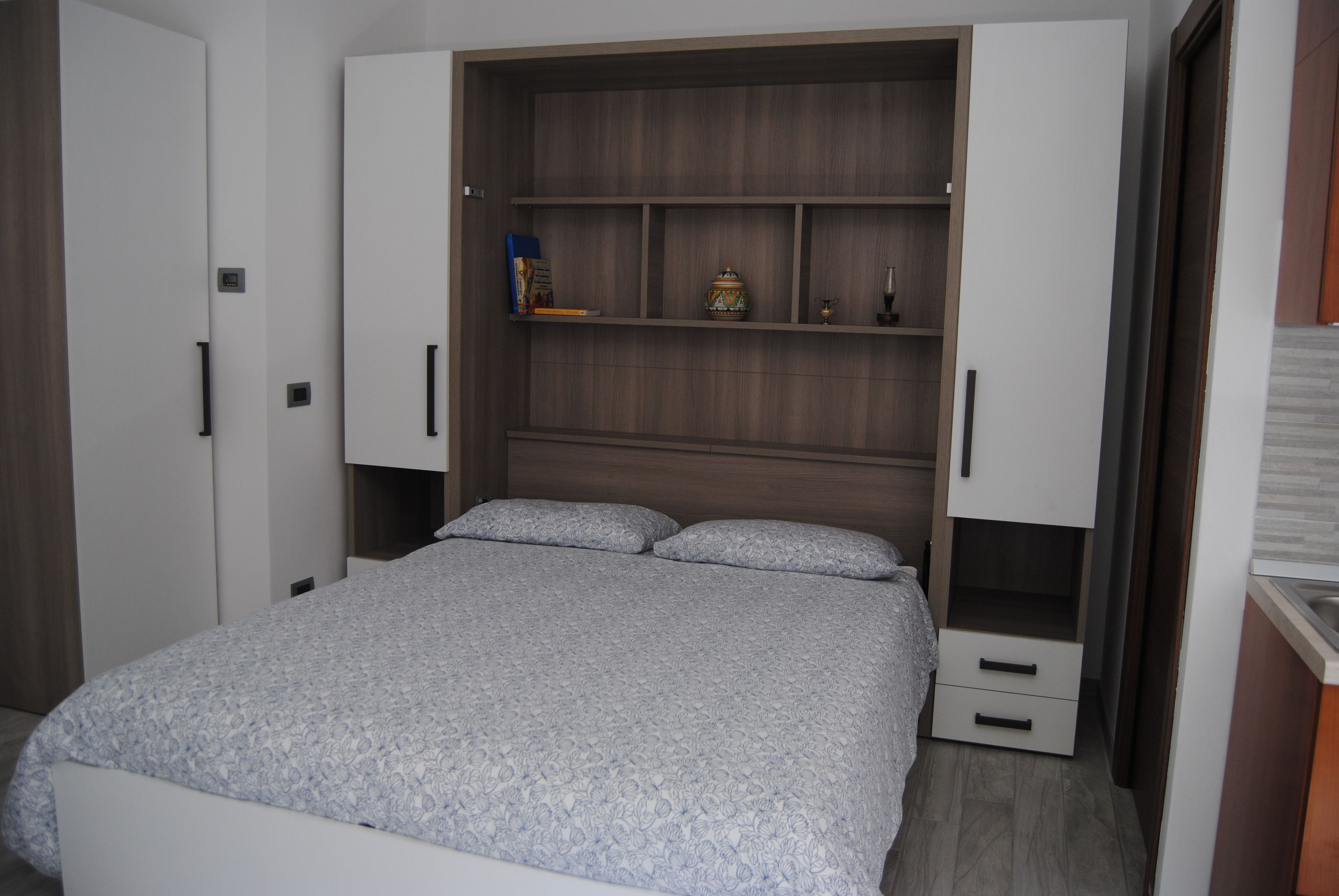 Una camera da letto con un letto, un armadio e una colonna contenitore a muro.