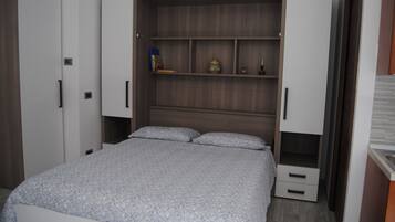 Una camera da letto con un letto, un armadio e una colonna contenitore a muro.